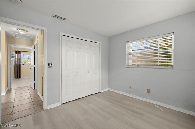 unfurnished bedroom with light wood-type flooring and a closet