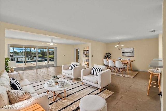 tiled living room with ceiling fan with notable chandelier