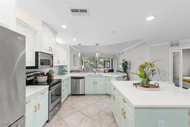 kitchen with a center island, kitchen peninsula, ornamental molding, and stainless steel appliances