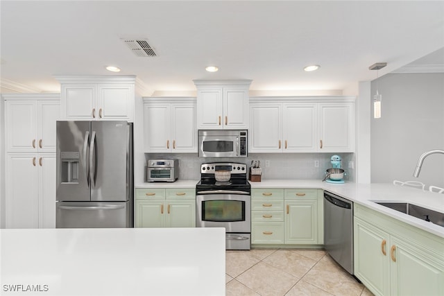 kitchen featuring ornamental molding, white cabinetry, appliances with stainless steel finishes, backsplash, and sink