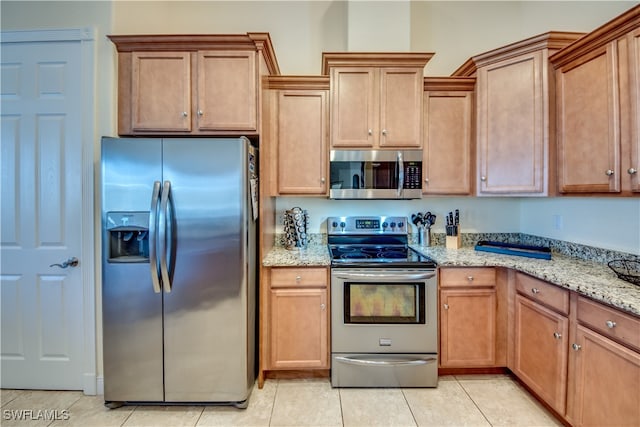 kitchen with light stone countertops, appliances with stainless steel finishes, and light tile patterned floors