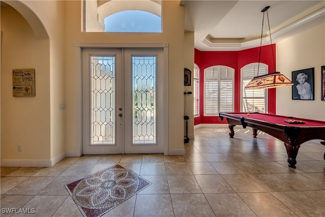 tiled foyer with a tray ceiling and french doors