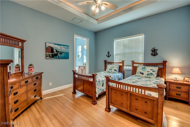 bedroom featuring ceiling fan, a raised ceiling, light wood-type flooring, and crown molding