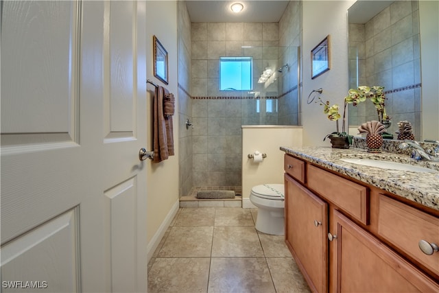 bathroom featuring tile patterned floors, toilet, vanity, and tiled shower