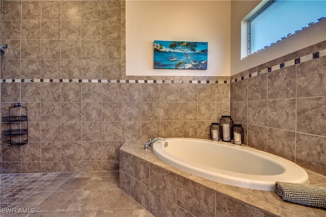 bathroom with tile walls and tiled bath