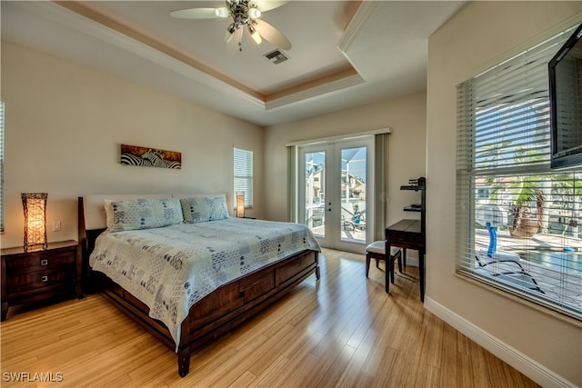 bedroom featuring french doors, access to outside, a raised ceiling, ceiling fan, and light hardwood / wood-style flooring