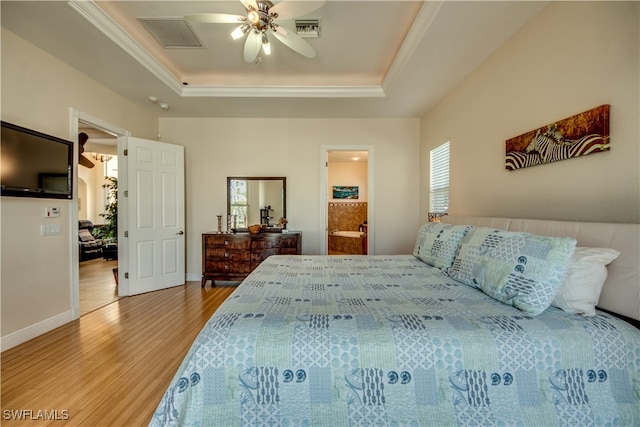 bedroom with a tray ceiling, multiple windows, ceiling fan, and hardwood / wood-style floors