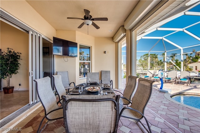 view of patio featuring ceiling fan and glass enclosure