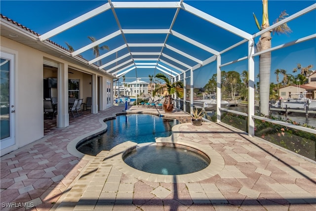 view of pool with glass enclosure, a water view, an in ground hot tub, and a patio