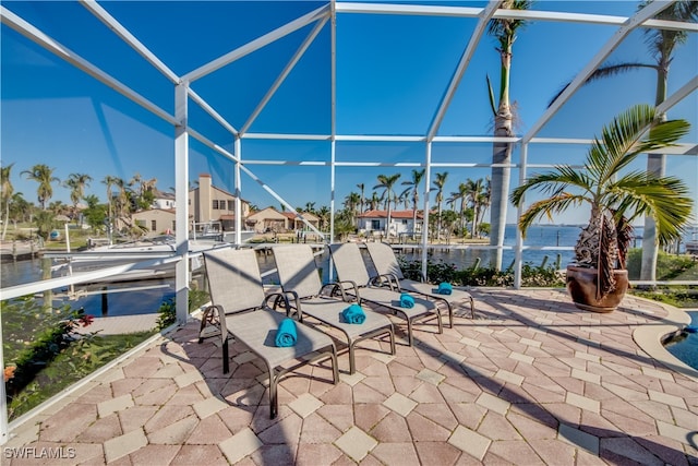 view of patio featuring a water view and glass enclosure