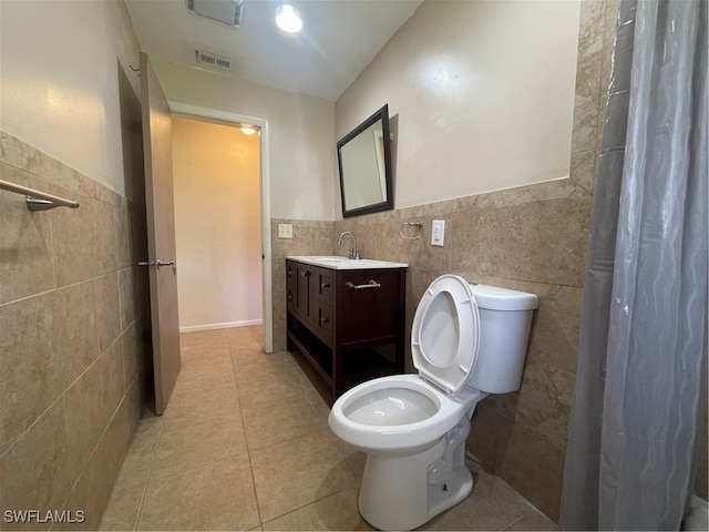 bathroom with tile walls, vanity, toilet, and tile patterned flooring