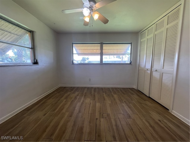 unfurnished bedroom with multiple windows, dark hardwood / wood-style floors, a closet, and ceiling fan