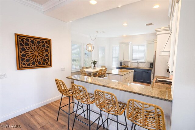 270 Delmar Ave, Fort Myers Beach, FL 33931 - kitchen featuring ornamental molding, wood finished floors, tasteful backsplash, a sink, and a breakfast bar