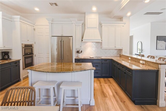 270 Delmar Ave, Fort Myers Beach, FL 33931 - kitchen featuring appliances with stainless steel finishes, a kitchen breakfast bar, light wood-style floors, light stone counters, and crown molding
