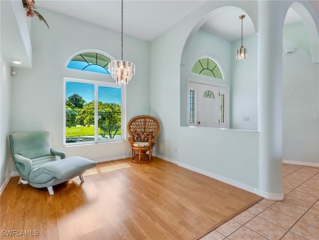 sitting room with a towering ceiling, light hardwood / wood-style flooring, and a notable chandelier