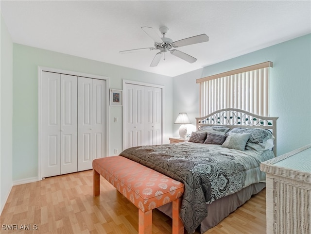 bedroom featuring two closets, light wood-type flooring, and ceiling fan