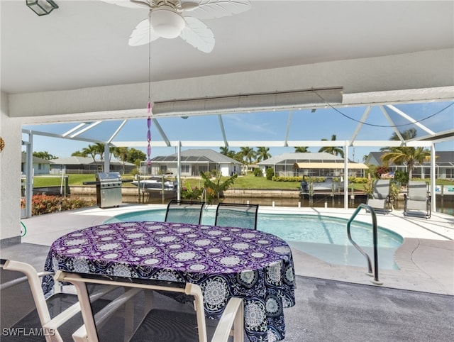 view of pool featuring a patio area, a water view, glass enclosure, and ceiling fan