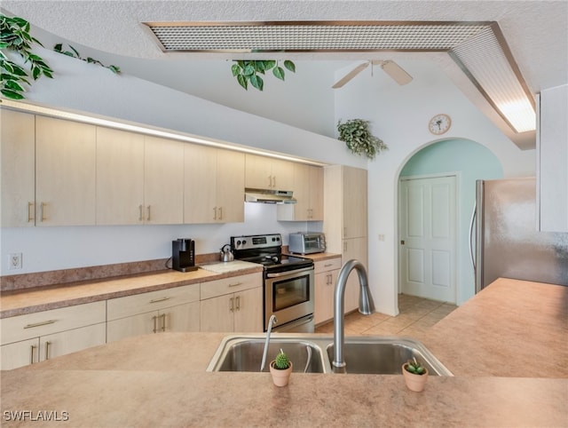 kitchen featuring sink, vaulted ceiling, appliances with stainless steel finishes, a textured ceiling, and ceiling fan