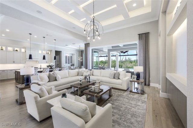 living room featuring light hardwood / wood-style flooring, ornamental molding, a chandelier, and coffered ceiling