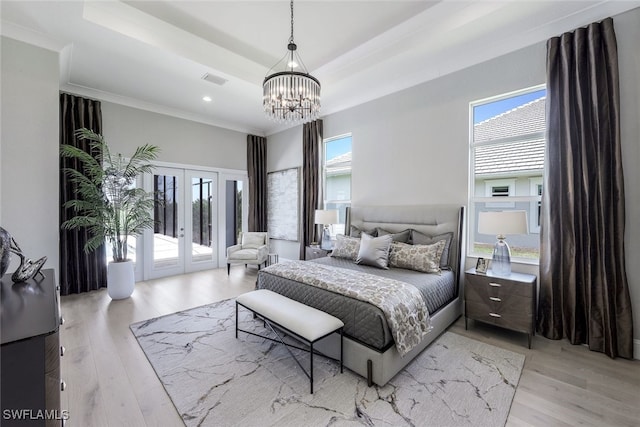 bedroom featuring french doors, a raised ceiling, access to outside, and light wood-type flooring