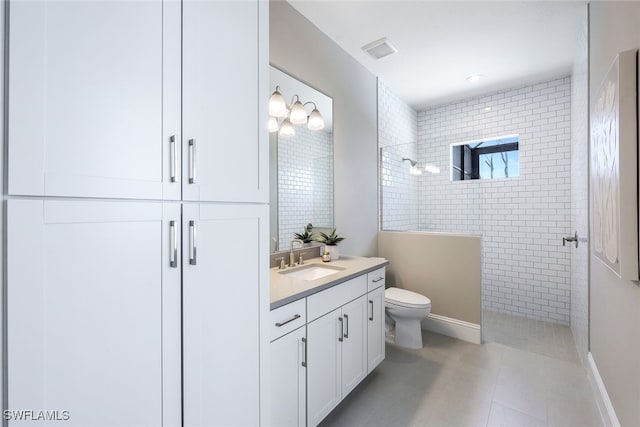 bathroom with vanity, tile patterned flooring, toilet, and tiled shower