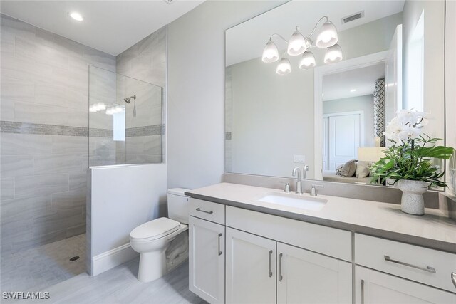 bathroom with vanity, toilet, and tiled shower