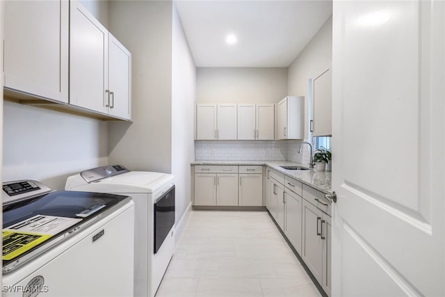 washroom with sink, washing machine and dryer, light tile patterned floors, and cabinets