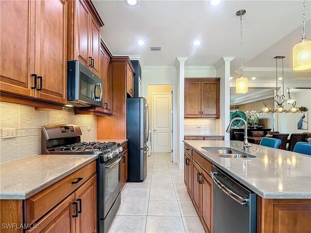 kitchen with pendant lighting, appliances with stainless steel finishes, light stone countertops, and sink