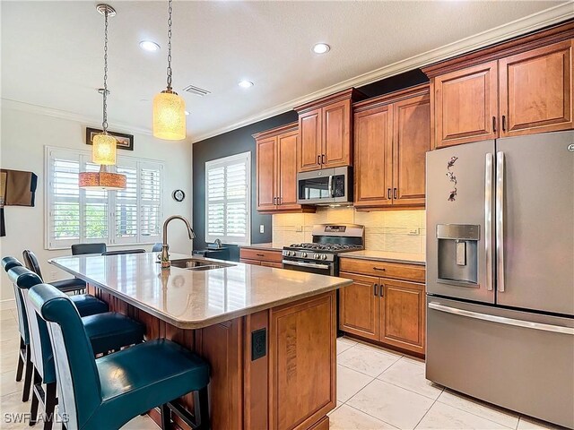 kitchen with appliances with stainless steel finishes, pendant lighting, an island with sink, sink, and a breakfast bar area