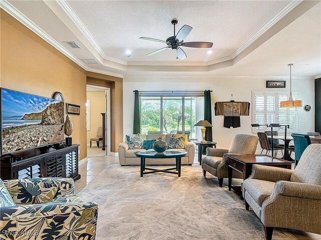 living room featuring a raised ceiling, crown molding, a wealth of natural light, and ceiling fan