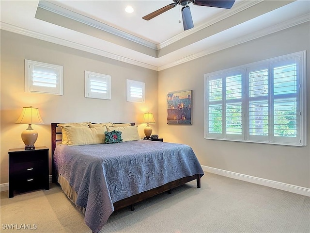 bedroom with ornamental molding, light carpet, ceiling fan, and a tray ceiling