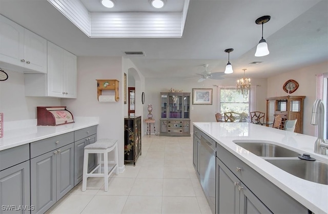 kitchen featuring hanging light fixtures, stainless steel dishwasher, sink, gray cabinets, and white cabinetry