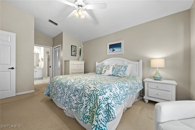 bedroom with ceiling fan, vaulted ceiling, a closet, ensuite bath, and light colored carpet