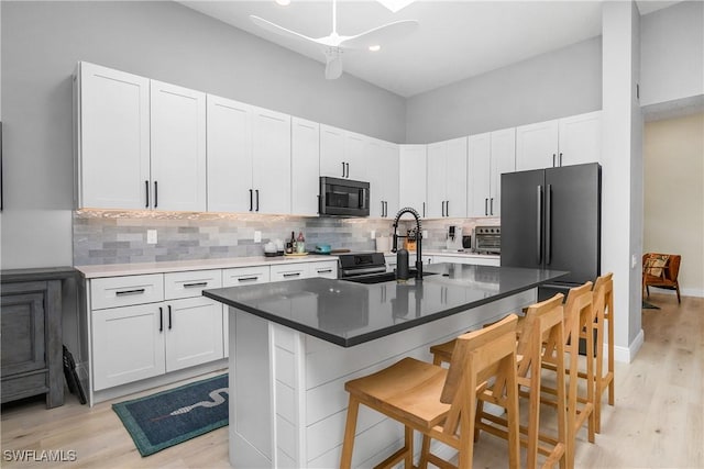 kitchen featuring a kitchen island with sink, a breakfast bar area, and white cabinets