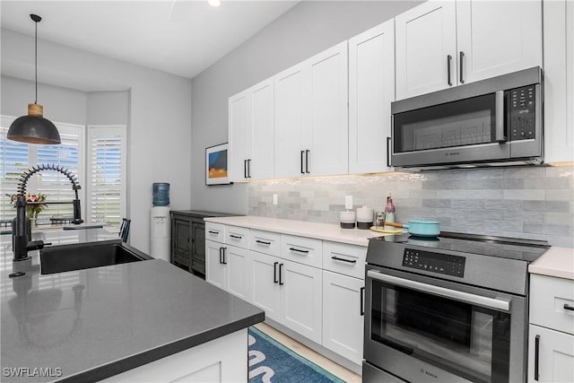 kitchen with sink, appliances with stainless steel finishes, pendant lighting, decorative backsplash, and white cabinets