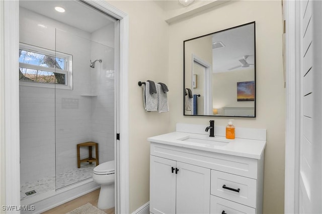 bathroom featuring vanity, toilet, and a tile shower