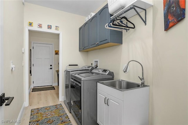 washroom with cabinets, sink, washing machine and clothes dryer, and light hardwood / wood-style floors