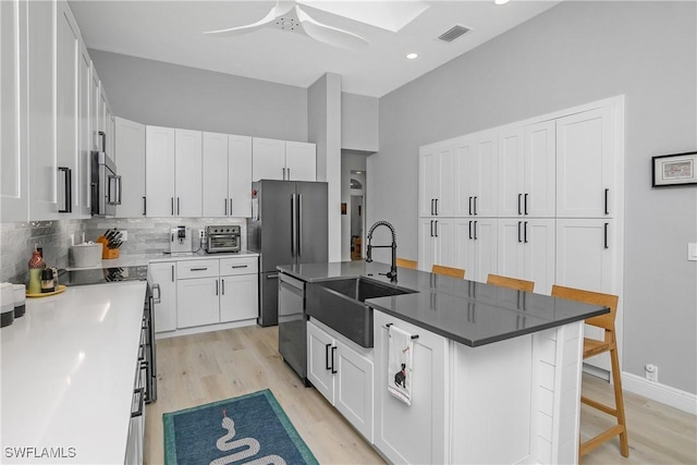 kitchen with white cabinetry, sink, a center island with sink, and a kitchen breakfast bar