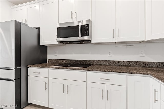 kitchen with white cabinets, stainless steel appliances, and dark stone counters