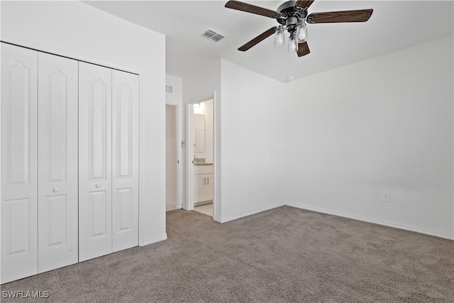 unfurnished bedroom featuring light carpet, a closet, ensuite bath, and ceiling fan