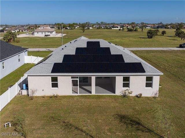 rear view of property with a yard and solar panels