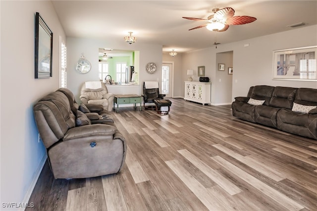 living room featuring ceiling fan with notable chandelier and hardwood / wood-style flooring