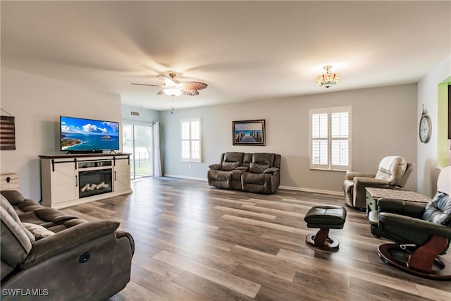 living room featuring ceiling fan, hardwood / wood-style flooring, a healthy amount of sunlight, and a fireplace