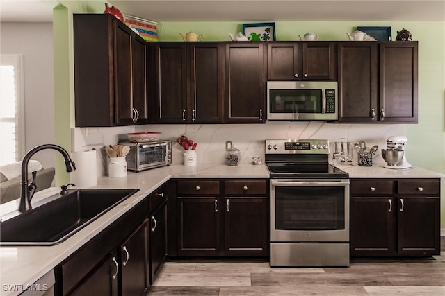 kitchen with dark brown cabinets, stainless steel appliances, and sink