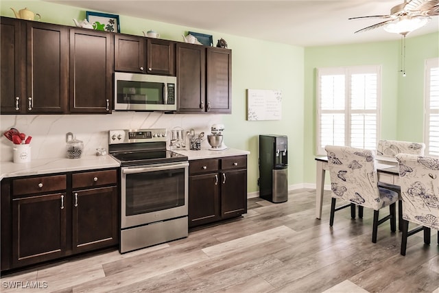 kitchen featuring stainless steel appliances, dark brown cabinets, light wood-type flooring, and decorative backsplash