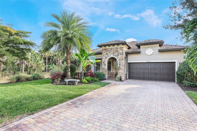 mediterranean / spanish house featuring decorative driveway, stucco siding, a garage, stone siding, and a front lawn