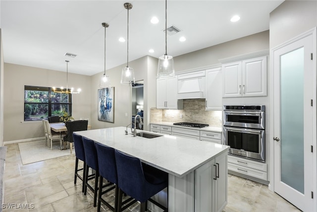 kitchen featuring stainless steel appliances, a sink, visible vents, white cabinetry, and custom exhaust hood