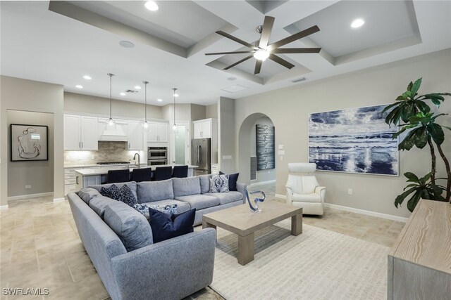 living room with beamed ceiling, ceiling fan, coffered ceiling, and sink