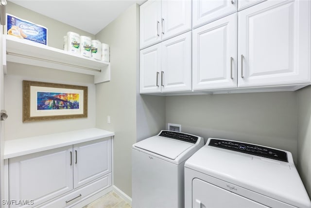 washroom with baseboards, cabinet space, and washer and dryer