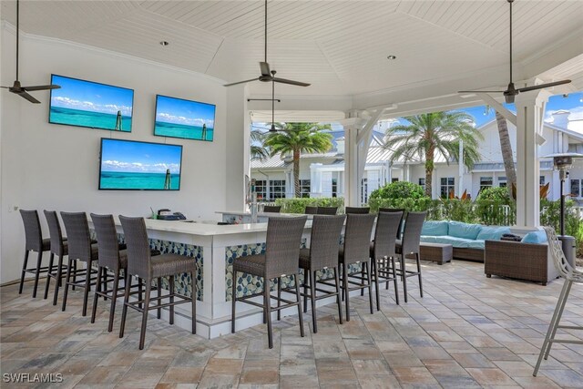 view of patio / terrace with a bar, outdoor lounge area, and ceiling fan